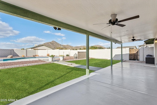 view of patio / terrace featuring a fenced backyard, a fenced in pool, a mountain view, and a ceiling fan