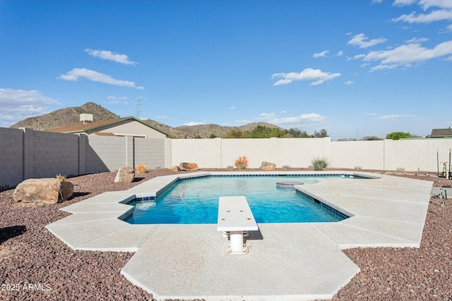 view of pool featuring a fenced in pool, a patio area, a mountain view, a fenced backyard, and a diving board