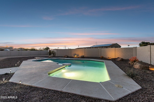 pool at dusk with a hot tub, a fenced in pool, a fenced backyard, a patio area, and a diving board