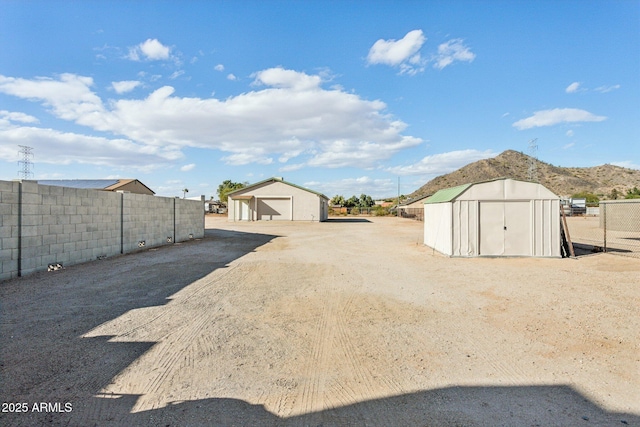 exterior space featuring a storage shed, a detached garage, fence, and an outbuilding