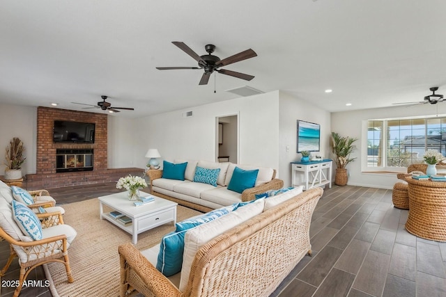 living area with recessed lighting, visible vents, a ceiling fan, wood tiled floor, and a brick fireplace