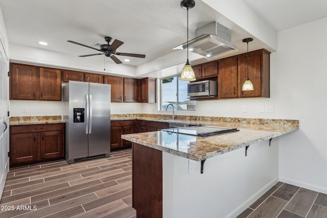 kitchen with a peninsula, appliances with stainless steel finishes, a sink, and wood finish floors