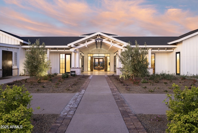 exterior entry at dusk with board and batten siding and a shingled roof