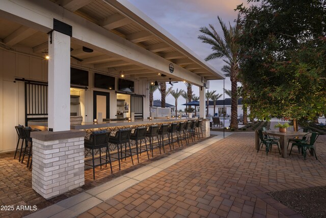 patio terrace at dusk featuring an outdoor bar