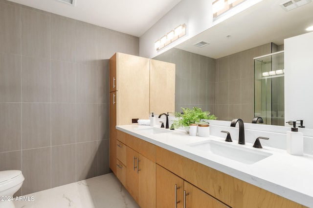 bathroom with vanity, a shower with shower door, toilet, and tile walls