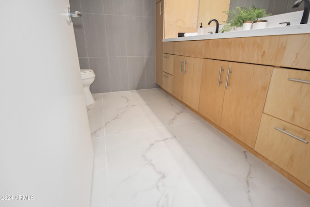 bathroom featuring toilet, vanity, and tile walls