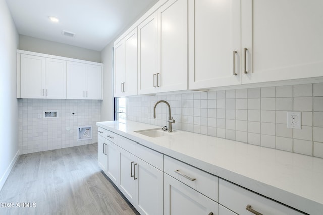 clothes washing area with sink, cabinets, hookup for a washing machine, hookup for an electric dryer, and light hardwood / wood-style floors