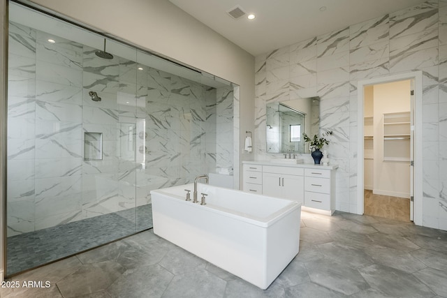 bathroom featuring vanity, plus walk in shower, and tile walls