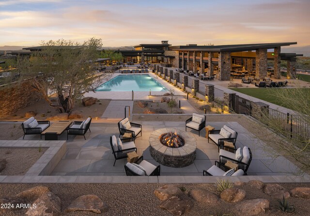 pool at dusk with a patio and an outdoor fire pit