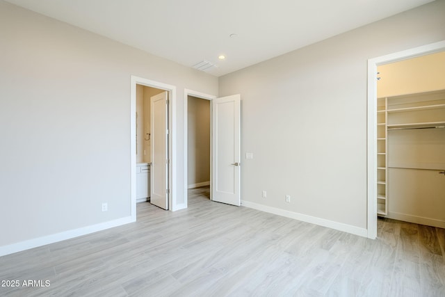 unfurnished bedroom with a walk in closet, light hardwood / wood-style floors, and a closet