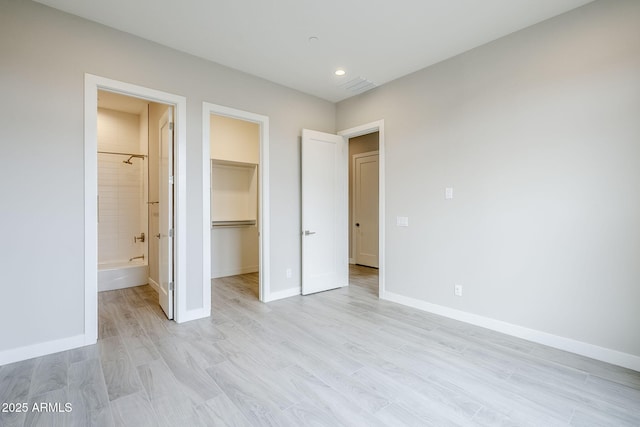 unfurnished bedroom with a spacious closet, light hardwood / wood-style floors, a closet, and ensuite bathroom