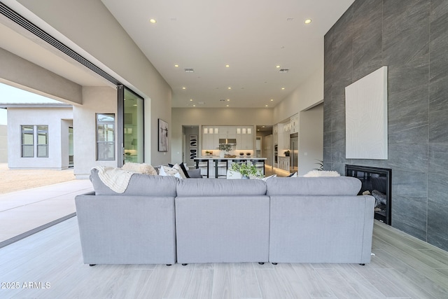 living room with a tiled fireplace and a towering ceiling