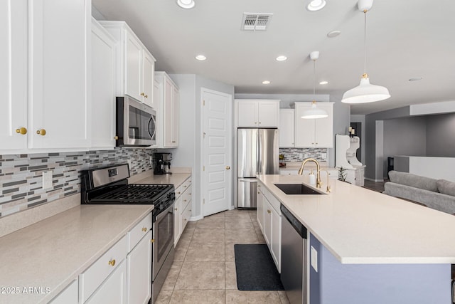 kitchen with appliances with stainless steel finishes, sink, a center island with sink, white cabinetry, and hanging light fixtures