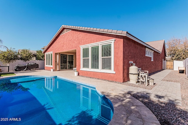 rear view of property with a fenced in pool and a patio area