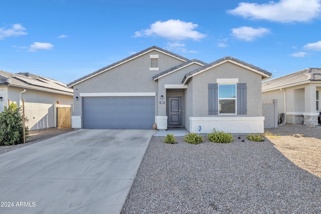 ranch-style home with driveway, an attached garage, fence, and stucco siding