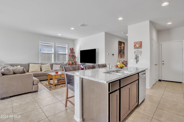 kitchen featuring light tile patterned floors, a sink, visible vents, open floor plan, and dishwasher