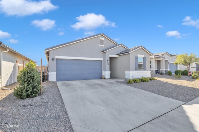 ranch-style home featuring an attached garage, fence, concrete driveway, a tiled roof, and stucco siding