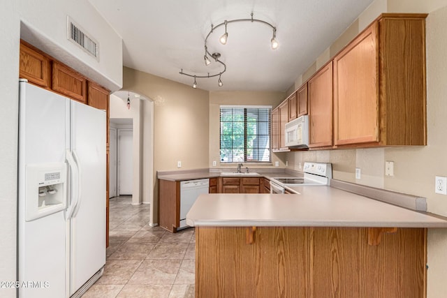 kitchen featuring visible vents, a peninsula, white appliances, light countertops, and a sink