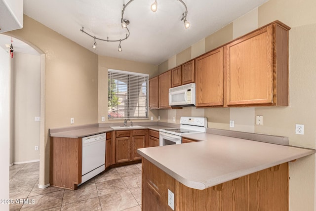 kitchen featuring a sink, light tile patterned floors, a peninsula, and white appliances