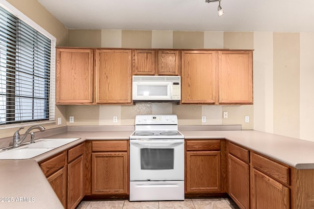 kitchen featuring a sink, light countertops, a peninsula, white appliances, and light tile patterned flooring