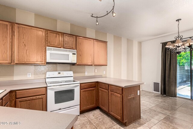 kitchen featuring a peninsula, white appliances, wallpapered walls, light countertops, and a chandelier