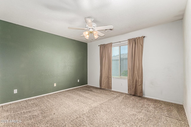 carpeted spare room featuring baseboards, ceiling fan, and visible vents