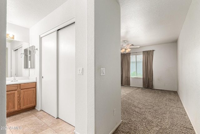 corridor featuring light carpet and a textured ceiling