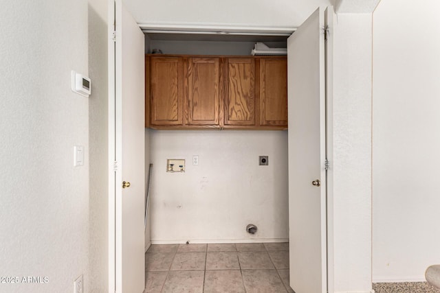washroom featuring electric dryer hookup, cabinet space, light tile patterned floors, baseboards, and hookup for a washing machine