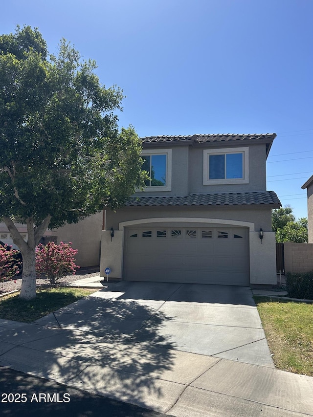 traditional-style home featuring a tiled roof, an attached garage, driveway, and stucco siding