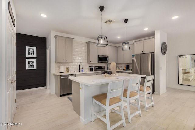 kitchen featuring appliances with stainless steel finishes, sink, gray cabinetry, and a kitchen island