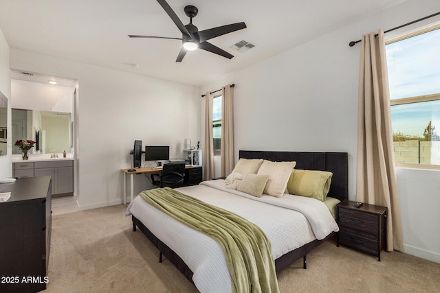 carpeted bedroom with ceiling fan, ensuite bathroom, and multiple windows