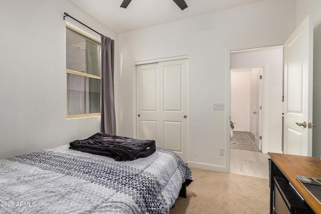 bedroom with ceiling fan, light colored carpet, and a closet