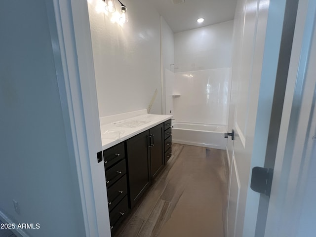 bathroom with bathing tub / shower combination, wood finished floors, and vanity