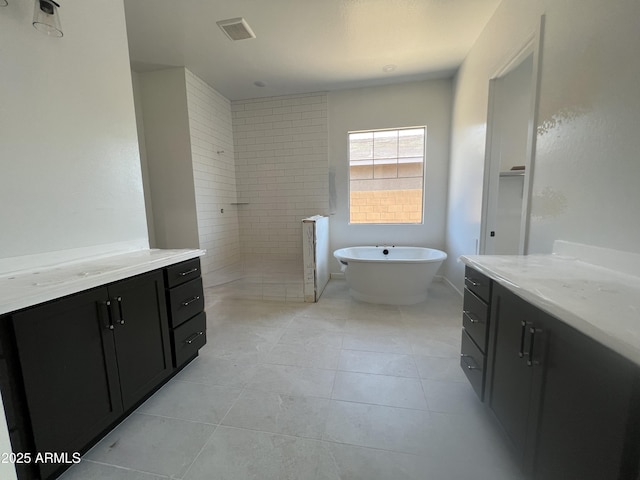 bathroom featuring visible vents, vanity, a walk in shower, tile patterned flooring, and a freestanding tub