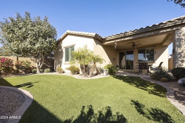 rear view of house with ceiling fan, a patio area, and a yard