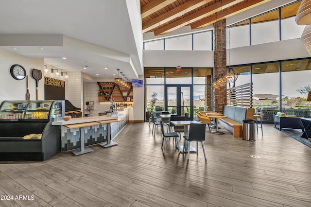 dining room featuring beam ceiling, high vaulted ceiling, a wealth of natural light, and hardwood / wood-style floors