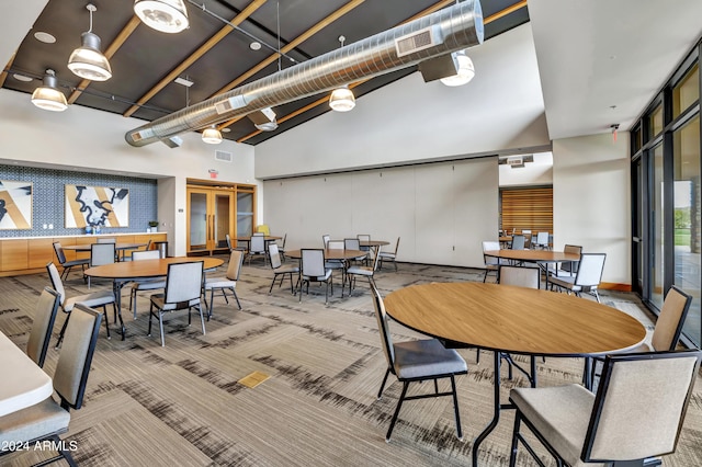 dining space with carpet floors and high vaulted ceiling