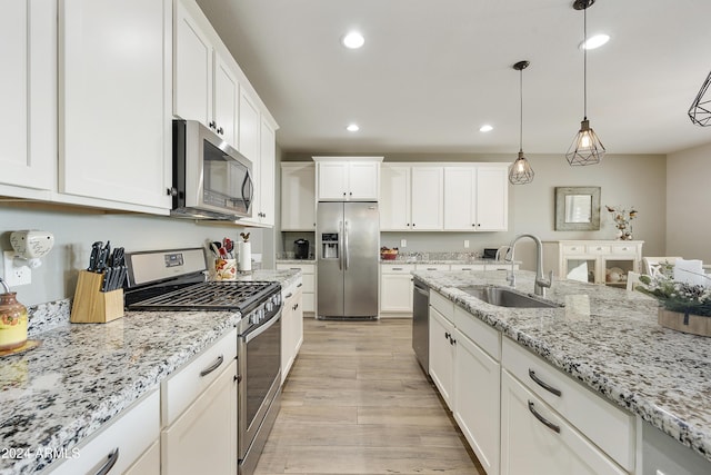 kitchen featuring pendant lighting, white cabinetry, sink, and appliances with stainless steel finishes