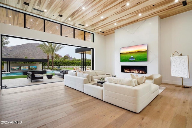 living room with wood ceiling, a mountain view, light wood-type flooring, and a high ceiling