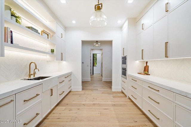 kitchen with white cabinetry, sink, and hanging light fixtures