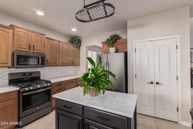 kitchen with a center island, stainless steel appliances, backsplash, and light tile patterned flooring