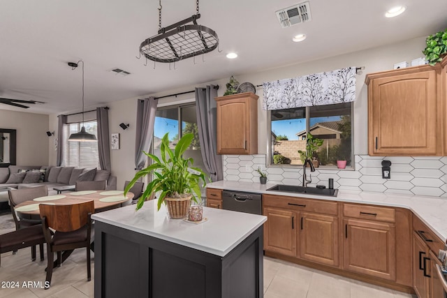 kitchen featuring dishwasher, a center island, sink, ceiling fan, and tasteful backsplash