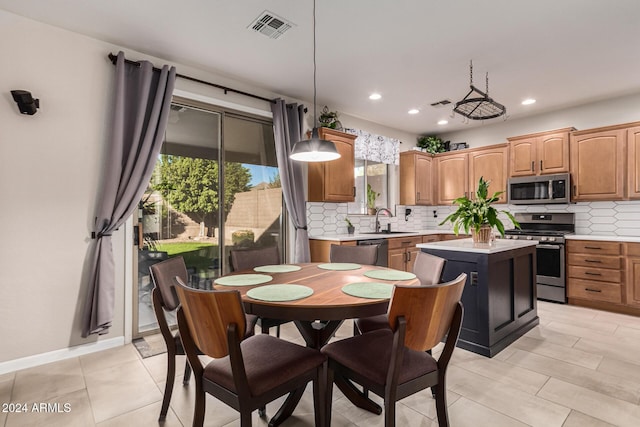 kitchen featuring appliances with stainless steel finishes, a center island, tasteful backsplash, and hanging light fixtures