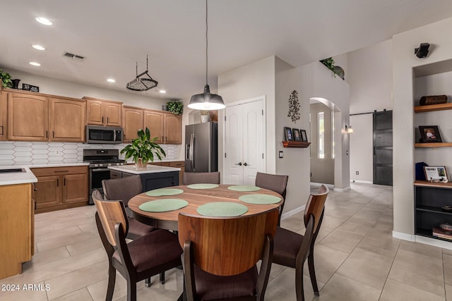 dining space featuring a barn door and light tile patterned flooring