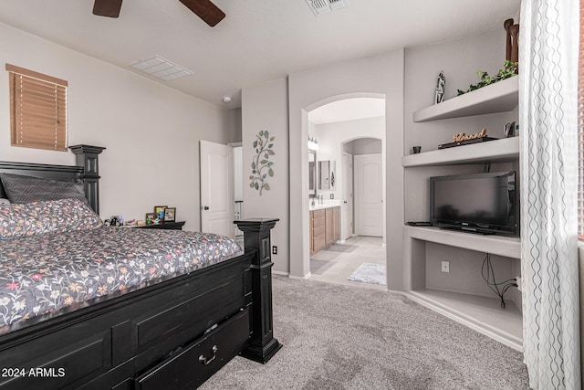 carpeted bedroom with ensuite bath and ceiling fan