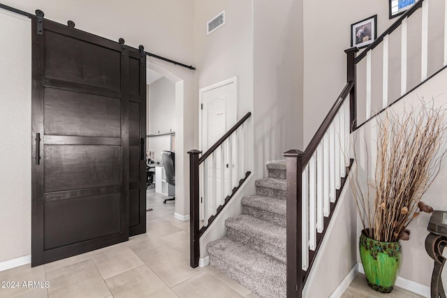 foyer entrance featuring a barn door, light tile patterned floors, and a high ceiling