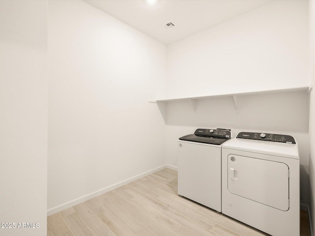 laundry room with washer and clothes dryer and light hardwood / wood-style floors