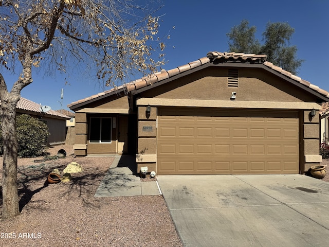 ranch-style home featuring concrete driveway, an attached garage, a tile roof, and stucco siding