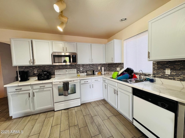 kitchen with white appliances, wood finish floors, a sink, light countertops, and white cabinets