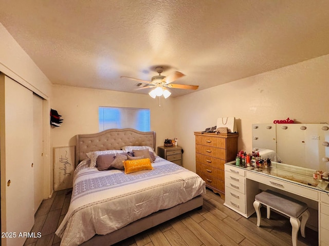 bedroom featuring ceiling fan, a closet, a textured ceiling, and wood finished floors